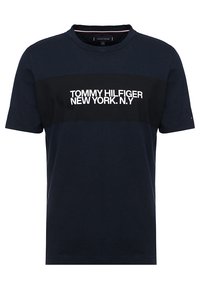 Mørkeblå T-shirt med korte ærmer og sort brystbånd samt hvid tekst "Tommy Hilfiger New York N.Y" på fronten.