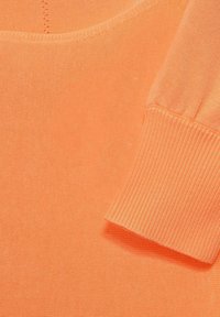 Orange stickad tröja med rundad halsringning och ribbade ärmslut. Slät textur med jämn söm och inga synliga mönster eller detaljer.