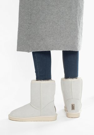 Graue Wildleder-Stiefeletten mit einem weichen Futter aus Fell und einer braunen Gummisohle, die ein gesticktes Muster und ein Markenetikett an der Ferse aufweisen.