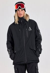 Black snow jacket with zip closure, adjustable drawstring hood, and multiple pockets. Features brand logo and contrasting white details.
