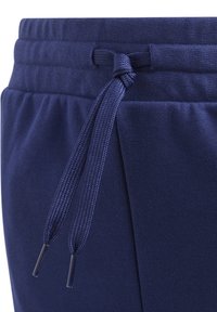 Tumedat sinised dressipüksid tekstuurse kangaga, elastse vöökoha ja reguleeritava nööriga. Kaks külgetaskut.