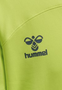 Jaskrawo limonkowa koszulka sportowa z teksturowanej tkaniny. Posiada ciemnoniebieskie logo "hummel" oraz stylizowany wzór pszczoły po lewej stronie na klatce piersiowej.