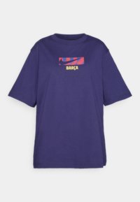 Violetti lyhythihainen T-paita, jossa on punainen ja sininen Nike swoosh -grafiikka ja "BARÇA"-teksti keltaisella rinnassa.