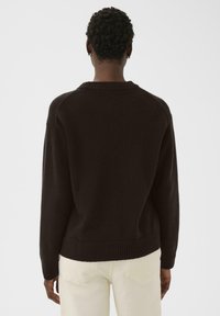 Dark brown knitted sweater with a ribbed hem and cuffs. Features a relaxed fit and a seamless design at the shoulders.