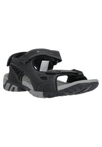 Musta sandaali säädettävillä remmeillä, harmaa kumipohja ja teksturoitu pohjallinen. Sisältää aukkoja hengittävyyden parantamiseksi ja kestävän suunnittelun.