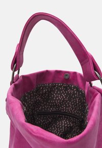 Różowa zamszowa torba tote z okrągłym uchwytem i czarną podszewką z różowym wzorem w kropki. Wewnątrz kieszeń na zamek do przechowywania.