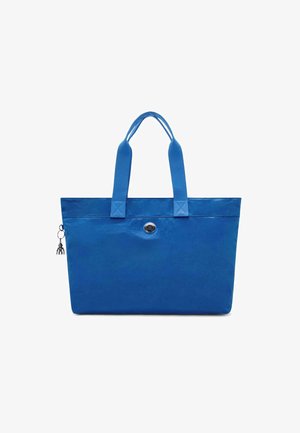 Blue tote bag made of smooth fabric, featuring two sturdy handles, a circular silver emblem, and a decorative charm attached to the zipper.