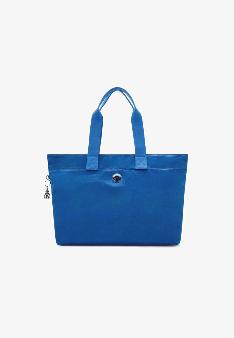 Niebieska torba na ramię wykonana z gładkiego materiału, z dwoma mocnymi uchwytami, okrągłym srebrnym emblematem oraz ozdobnym brelokiem przypiętym do zamka.