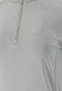 Hellgraues Kurzarmshirt mit einem halbseitigen Reißverschluss am Kragen, ausgestattet mit Flachnähte und einer glatten Textur. Minimalistisches Design ohne Muster.