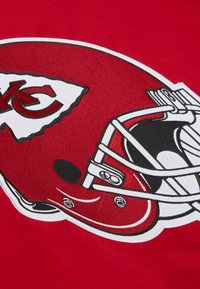 Roter Stoff mit einem Design eines Footballhelms der Kansas City Chiefs. Der Helm ist mit weißen, schwarzen und grauen Details akzentuiert.