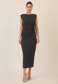 Schwarzes ärmelloses Kleid mit Rundhalsausschnitt, das mit einem gedrehten Frontdetail und einer figurnahen Silhouette begeistert, die bis zur Mitte der Waden reicht.