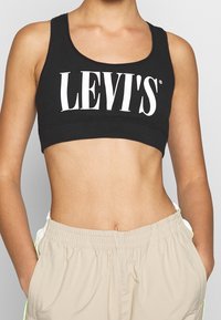 Svart crop top med en stor vit "LEVI'S" logotyp framtill, tillverkad av mjuk bomull, med en åtsittande och stretchig design.