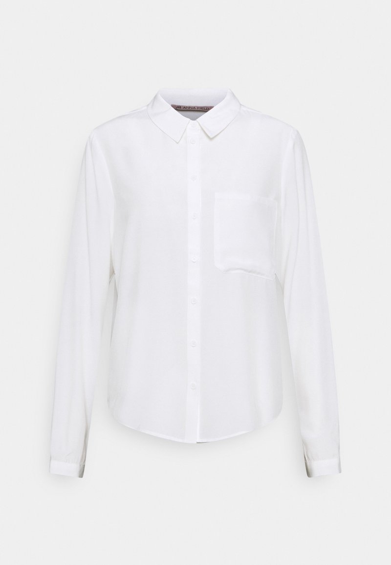 Weiße Bluse mit langen Ärmeln aus glattem Stoff, ausgestattet mit einem klassischen Kragen, einer Knopföffnung auf der Vorderseite und einer einzelnen Brusttasche.