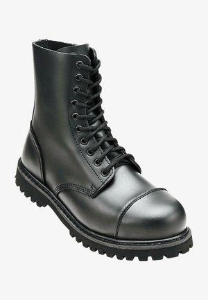 Botte de combat en cuir noir avec une tige haute, bout rond, laçage sur le devant et semelle en caoutchouc robuste avec un profil de crantage profond pour une meilleure adhérence.