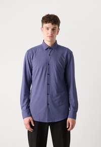 Camisa de botones azul marino con lunares blancos, de manga larga y cuello puntiagudo. Presenta botones negros y una tela suave y tejida.
