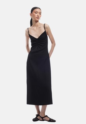 Czarna midi sukienka na ramiączkach, z głębokim dekoltem w kształcie litery V i marszczonym przodem, wykonana z teksturowanej tkaniny.