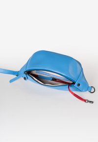 Borsa di pelle blu con una superficie liscia, chiusura con zip e una tracolla con accentuazione rossa. L'interno presenta più scomparti per un'organizzazione ottimale.