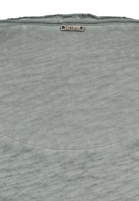 Jasnoszara koszulka z miękkiego, teksturowanego materiału. Posiada okrągły dekolt oraz wytłoczoną metkę "Key Largo" blisko kołnierza.