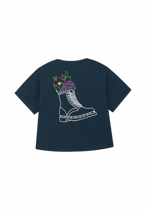 Marineblauw t-shirt met een witte omtrek van een laars waar kleurrijke bloemen uitkomen, wat de mix van mode en natuur benadrukt.