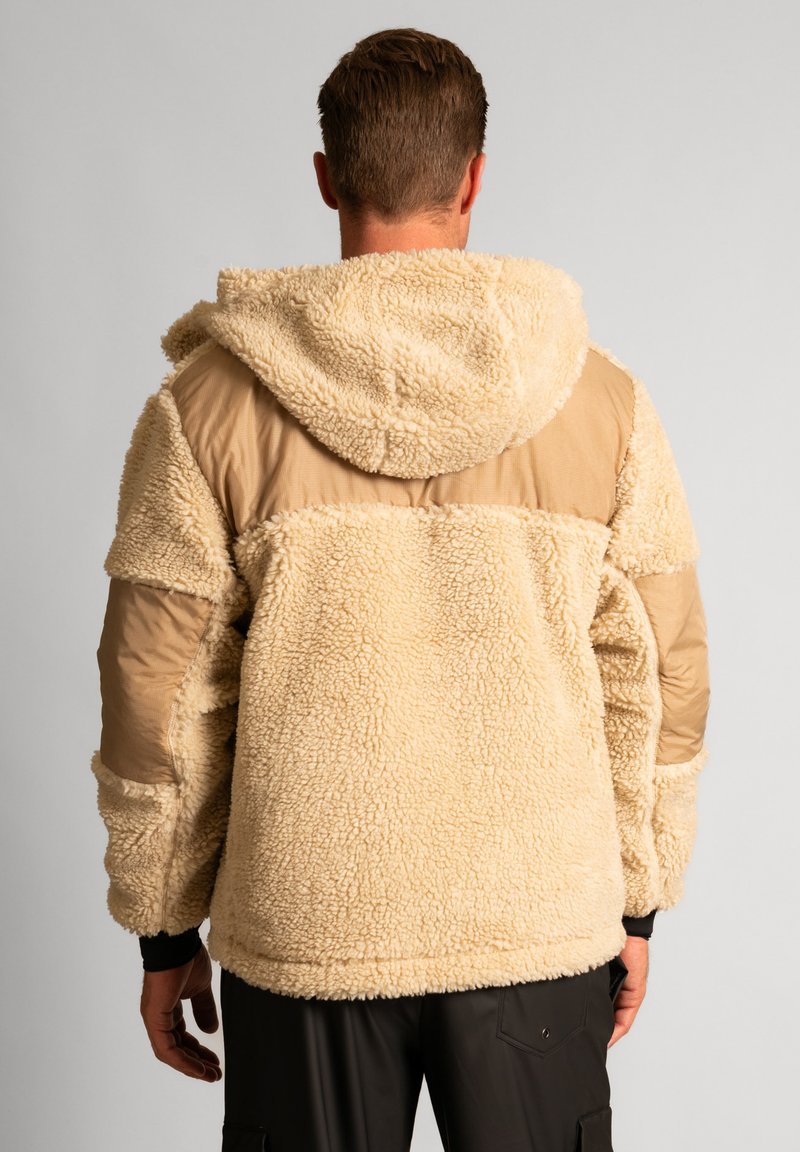 Giacca in pile color crema con finitura testurizzata e pannello in nylon beige. Dotata di cappuccio e polsini a costine. Materiale morbido e spesso.