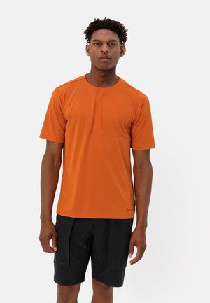Korte mouwen, oranje t-shirt met een ronde hals en een klein borstzakje, gecombineerd met zwarte shorts met klepzakken. Lichtgewicht stof.