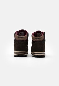 Brązowe zamszowe i tekstylne botki z wysoką cholewką, wyściełanym kołnierzem i beżowymi akcentami. Posiadają teksturowany czubek oraz kontrastową czarną podeszwę.