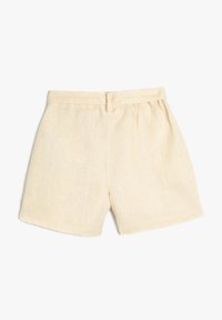 Pantalones cortos de lino en un beige claro, con una cinturilla ajustada y un corte relajado, que muestran una textura visible y sin bolsillos ni adornos.