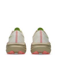 Des chaussures de course beiges avec des tiges en maille, des détails en rose et des accents vert clair. Semelles beiges épaisses avec des sections de talon rouges.