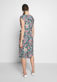 Abito floreale in teal con maniche corte, vita sfiancata e orlo all'altezza del ginocchio. Presenta motivi di fiori rosa e bianchi e una cintura annodata.