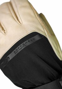 Handschoen met een lichtbeige lederen palm en een lichaam van zwart softshellmateriaal, met een textuur en een elastische pols voor een stevige pasvorm.