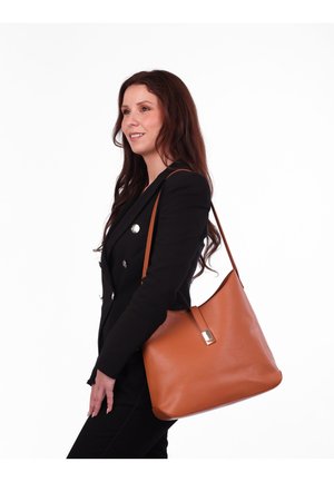 Hnědá kožená kabelka přes rameno s hladkým povrchem, uvolněným tvarem a kovovým akcentem na přední straně. Nastavitelný ramenní popruh.