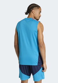 Blue athletic sleeveless top with a smooth texture; paired with navy shorts featuring a geometric pattern and contrasting lighter blue accents.
