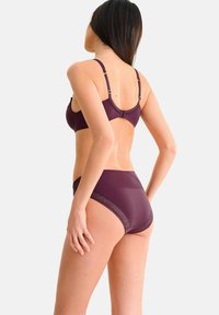 Ensemble de lingerie bordeaux comprenant un soutien-gorge à bretelles ajustables et des détails en dentelle complexes, associé à un slip taille haute mettant en avant un accent à motifs.