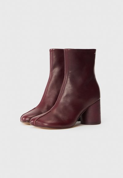 Bottines en cuir bourgogne avec une texture lisse, bouts carrés et un talon en bois chunky. Des détails de couture courent le long du côté extérieur.