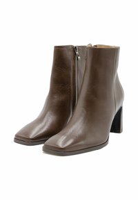 Een paar bruine leren enkelboots met vierkante neuzen, ritsen aan de zijkant en blokhakken op een witte achtergrond.