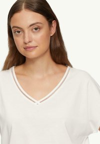 Witte katoenen t-shirt met een V-hals, voorzien van een decoratieve stiksel langs de kraag en een losse pasvorm.