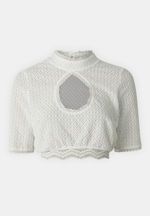 Valkoinen lyhytcropattu paita, jossa on teksturoitu timanttikuvio, korkea kaulus, lyhyet hihat ja avainreikäyksityiskohta keskellä. Aaltomaisesti leikattu helma.
