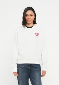 Λευκό φούτερ με στρογγυλή λαιμόκοψη, με ροζ λογότυπο καρδιάς με εφέ που στάζει στο αριστερό στήθος. Βαμβακερό υλικό, άνετη εφαρμογή.