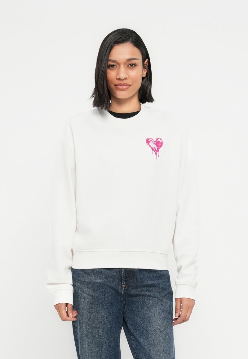 Λευκό φούτερ με στρογγυλή λαιμόκοψη, με ροζ λογότυπο καρδιάς με εφέ που στάζει στο αριστερό στήθος. Βαμβακερό υλικό, άνετη εφαρμογή.