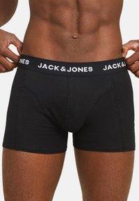 Boxer-briefs noirs en tissu doux, avec une large ceinture élastique portant le texte "JACK & JONES" en blanc, et une coupe ajustée.