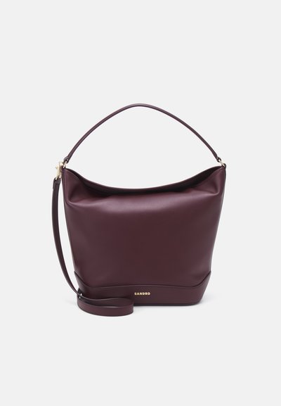 Borsa in pelle bordeaux con una struttura morbida, parte superiore curva, manico corto e tracolla removibile, caratterizzata da un logo dorato nella parte inferiore.