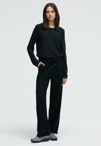 Schwarzes, geripptes Strick-Loungewear-Set mit einem Langarm-Oberteil mit rundem Ausschnitt und Hosen mit elastischem Bund und Kordelzug.