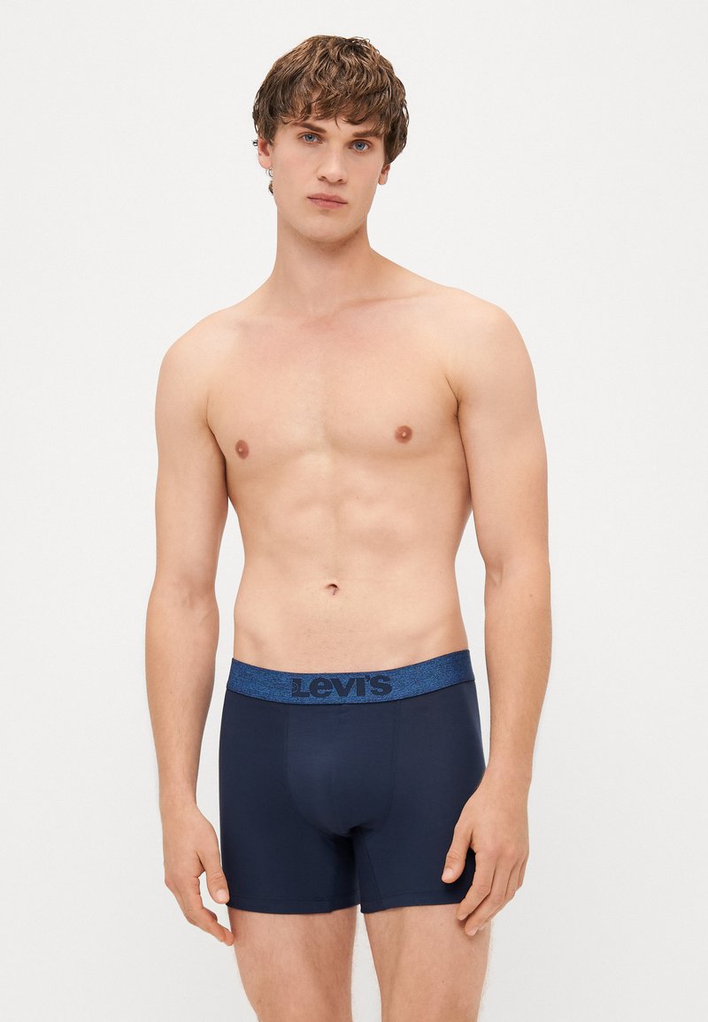 Sötétkék boxernadrág texturált kék derékpánttal, amelyen a Levi's logó található. Simább anyag és testhezálló fazon rövid lábakkal.
