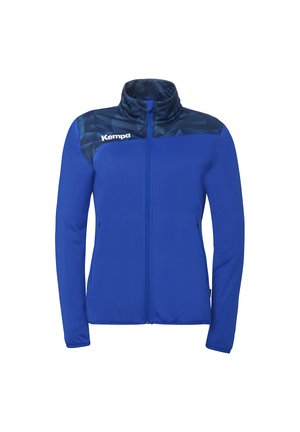 Blauw sportjack met volledige ritssluiting, donker geometrisch patroon op het juk en wit Kempa-logo op de linkerborst.