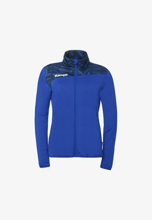 Blauw sportjack met volledige ritssluiting, donker geometrisch patroon op het juk en wit Kempa-logo op de linkerborst.