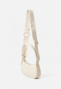 Bolso cruzado color crema con superficie texturizada, correa ajustable, herrajes dorados y detalles de logo en relieve. Diseño compacto.