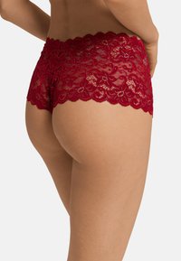 Červené krajkové hipster šortky s květinovými vzory, vlnitým okrajem a průhlednou texturou, navržené pro pohodlné nošení.