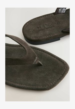 Infradito marroni scuri con texture scamosciata e un distintivo ponte, con il nome del marchio "NEXT" impresso sulla suola.