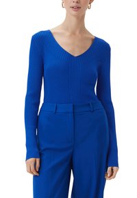 Królewsko-niebieski sweter prążkowany z głębokim dekoltem w kształcie litery V i długimi rękawami, w połączeniu z królewsko-niebieskimi spodniami dopasowanymi. Gładka tekstura, dopasowany krój.