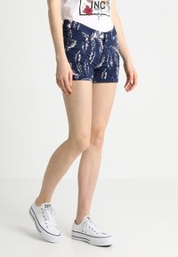 Krátné nohavice s květinovým vzorem v námořnické modré barvě, vyrobené z lehké tkaniny s přiléhavým střihem, vybavené předními kapsami a zapínáním na zip.